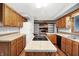 Spacious kitchen featuring wood cabinetry, island cooktop, and open view to the fireplace room at 11469 Woodview Ct, Fishers, IN 46038