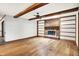 Living room featuring wood floors, a brick fireplace, built-in shelves, and exposed beams at 11469 Woodview Ct, Fishers, IN 46038