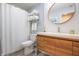 This is a bathroom with wood vanity, large round mirror, soft blue walls and a white shower curtain at 11911 W Grandview Dr, Columbus, IN 47201