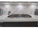 Close-up showcasing quartz countertop, stainless steel cooktop, and stylish backsplash at 11911 W Grandview Dr, Columbus, IN 47201