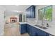 Eat-in kitchen with blue cabinets, stainless steel sink, and an open view into the living room with fireplace at 12524 Trophy Dr, Fishers, IN 46038