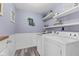 Charming laundry room with wainscoting, white appliances, wood-look floors, and decorative shelving at 12524 Trophy Dr, Fishers, IN 46038