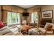 Bright living room featuring a rustic wood coffee table, cozy seating, and large windows showcasing a lush outdoor view at 12539 Pebblepointe Pass, Carmel, IN 46033