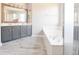 Bathroom featuring a double vanity, soaking tub, and wood-look floors at 12677 Honors Dr, Carmel, IN 46033