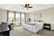 A bright main bedroom features a tray ceiling, ceiling fan, and a sitting area by the windows at 14499 Milton Rd, Fishers, IN 46037