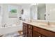 Bright bathroom featuring a soaking tub, double sink vanity, tan walls, and wood look flooring at 1468 Blackthorne N Trl, Plainfield, IN 46168
