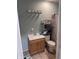 Bright bathroom featuring a wood vanity with a white sink, matching toilet, shelving, and curtained shower at 2208 S F St, Elwood, IN 46036