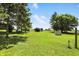 Lush green backyard with mature trees and outbuildings under a clear blue sky offer a serene outdoor space at 25420 Jerkwater Rd, Sheridan, IN 46069