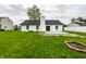 The backyard features a well-manicured lawn, a brick fire pit, and a freshly poured concrete patio at 321 Virginia St, Fortville, IN 46040