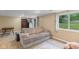 View of the finished basement with carpet and a comfortable gray couch next to a window to the backyard at 426 Tipton Ln, Columbus, IN 47201