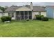 Home's backyard featuring a screened in porch and a large green lawn at 540 Cahill Ln, Indianapolis, IN 46214
