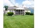 Backyard featuring a screened porch, trimmed bushes, green grass, and neighboring homes at 540 Cahill Ln, Indianapolis, IN 46214