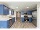 Updated kitchen with stainless steel appliances, ample countertop space, blue cabinets, and modern flooring at 671 Greenway St, Greenwood, IN 46143