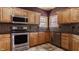 Well-lit kitchen featuring stainless steel appliances, natural lighting, dark backsplash, and wooden cabinets at 719 E New Rd, Greenfield, IN 46140