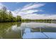 Scenic lake view from the dock featuring calm water, lush trees, and a clear blue sky with wispy clouds at 719 E New Rd, Greenfield, IN 46140