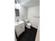 Modern half bathroom features a white vanity, updated fixtures, and black tile flooring at 909 N Temple Ave, Indianapolis, IN 46201