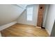 Bright bedroom featuring a window, hardwood floors, and a rustic brick accent wall at 909 N Temple Ave, Indianapolis, IN 46201