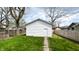 A detached garage with white siding, accessed by a stone pathway through a green lawn at 909 N Temple Ave, Indianapolis, IN 46201