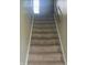 Carpeted staircase with a wooden handrail provides safe access to the upper levels of the home at 922 Eagle Brook Dr, Shelbyville, IN 46176
