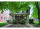 Charming two-story home featuring a covered porch and landscaped front yard with mature trees at 925 Fayette St, Indianapolis, IN 46202