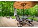 Charming backyard deck featuring an outdoor umbrella table, lush trees, and a cozy setting at 9445 Moorings Blvd, Indianapolis, IN 46256