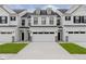 A townhome with white siding, black accents, and a two car garage, showcasing modern curb appeal at 9741 Oleander Dr, Fishers, IN 46250