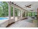 A screened-in porch with a ceiling fan offers a view of the pool and trees with a staircase leading to the deck at 11227 Woods Bay Ln, Indianapolis, IN 46236