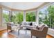 Bright sun room with hardwood floors, large windows, and a view of the lush greenery outside at 11227 Woods Bay Ln, Indianapolis, IN 46236