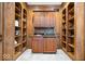 Elegant wet bar with custom wood cabinetry, shelving, a sink, and a small refrigerator at 11227 Woods Bay Ln, Indianapolis, IN 46236