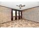 Bedroom featuring three windows with dark curtains, wood-paneled walls, and tile flooring at 11309 N County Road 750 W, Elwood, IN 46036