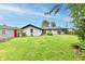 Back exterior view of home with red trimmed doors & windows, along with an adjacent shed and green lawn at 11309 N County Road 750 W, Elwood, IN 46036