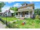 Inviting two-story home with a classic front porch, surrounded by lush greenery and a well-manicured lawn at 1138 N Oxford St, Indianapolis, IN 46201