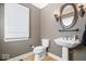 Elegant powder room with pedestal sink, decorative mirror, sconces, and toilet with a modern design at 11404 Hanbury Manor Blvd, Noblesville, IN 46060