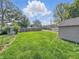Spacious backyard with green grass, a chain-link fence and a detached garage under a beautiful sky at 145 S 7Th Ave, Beech Grove, IN 46107