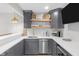 Stylish kitchenette featuring gray cabinets, stainless steel appliances, a sink, and floating wood shelves at 14931 W Black Wolf Run Dr, Carmel, IN 46033