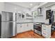 Well-lit kitchen with white cabinets, stainless steel appliances, subway tile, and wood flooring at 1627 Pleasant St, Indianapolis, IN 46203