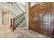 Grand foyer with a wooden staircase, detailed iron railings, tile flooring, and impressive wood double doors at 16332 Valhalla Dr, Noblesville, IN 46060