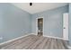 A spacious bedroom with light blue walls and wood-look laminate flooring, with a door to a bathroom at 2429 N Centennial St, Indianapolis, IN 46222