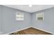 Bright bedroom featuring wood-look floors, light-blue walls, and two windows providing natural light at 3106 N Harding St, Indianapolis, IN 46208