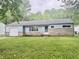 Charming single-story home with a stone facade and attached garage, surrounded by lush greenery at 3325 Canaday Dr, Anderson, IN 46013
