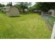 Expansive backyard with lush green grass and multiple storage sheds surrounded by fencing at 3612 Carolee Ct, Indianapolis, IN 46227