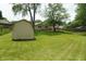 Large backyard with a storage shed, green grass, and mature trees, offering plenty of space at 3612 Carolee Ct, Indianapolis, IN 46227