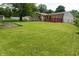 A spacious backyard, featuring a red deck, and mature trees at 3612 Carolee Ct, Indianapolis, IN 46227