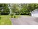 A view of the property's long driveway, grassy front yard, and detached garage at 4244 Asbury St, Indianapolis, IN 46227