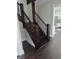 View of the staircase featuring dark wood steps and decorative balusters, adjacent to an entrance to the kitchen at 4303 W County Road 200 S Rd, Danville, IN 46122
