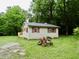 A cozy house surrounded by a vibrant green yard with mature trees and charming wood accents at 4675 N Herbemont Rd, Martinsville, IN 46151