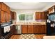 Functional kitchen with wood cabinets, a black appliance suite, and laminate flooring at 4701 Candy Spots Dr, Indianapolis, IN 46237