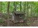 An outbuilding features gray walls and a peaked roof amid lush green forest foliage at 5640 High Vista Cir, Indianapolis, IN 46234