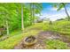 Green backyard with an elevated fire pit, trees, and a view of the house at 5739 Paradise Dr, Martinsville, IN 46151