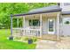 Covered front porch seating area with a landscaped front yard and flowers at 5739 Paradise Dr, Martinsville, IN 46151